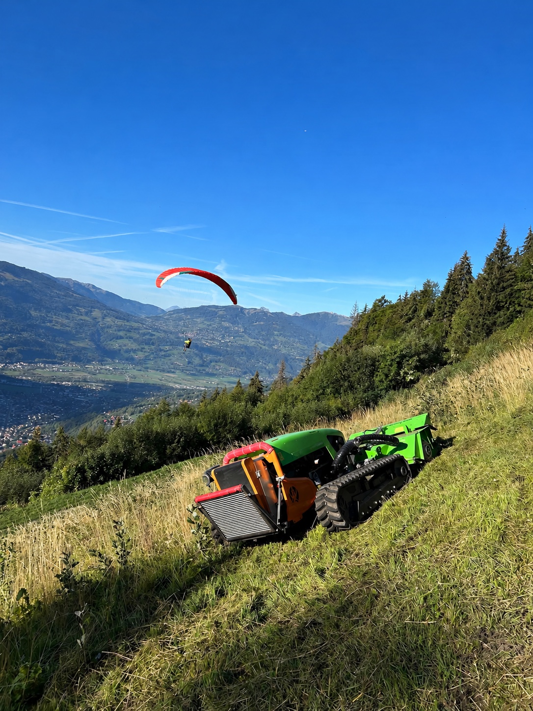 Robot de broyage sur un versant herbeux en montagne